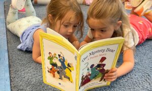 girls reading a book at a preschool in Coral Gables